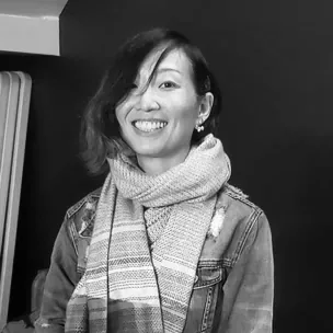 Anita Tong souriante lors d’une prestation en direct, en veste en jean et écharpe tricotée