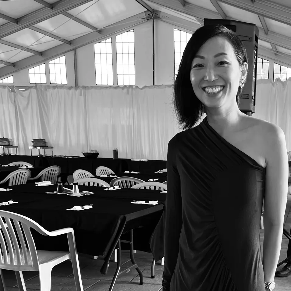 Anita Tong en robe à une épaule sous un chapiteau de réception