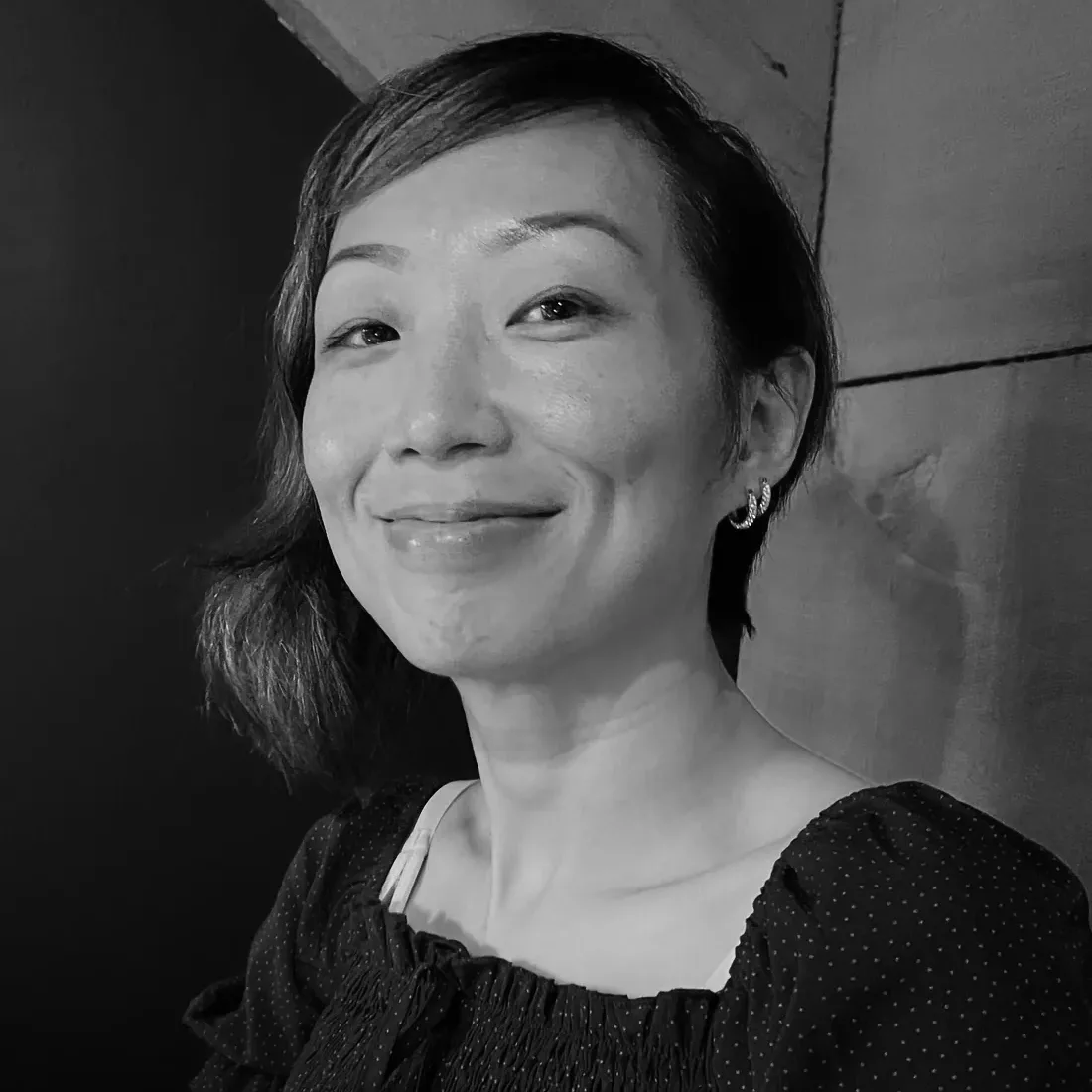 Anita Tong souriante dans un haut à motifs