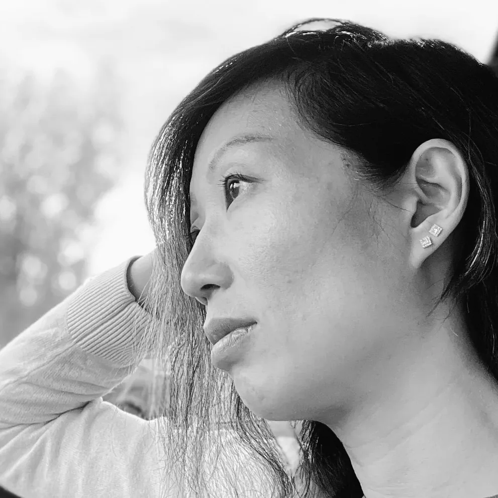 Anita Tong de profil en extérieur, les arbres flous derrière elle