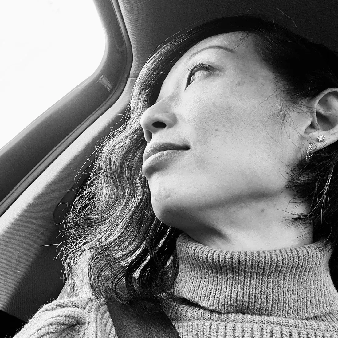 Anita Tong le regard levé, en col roulé tricoté