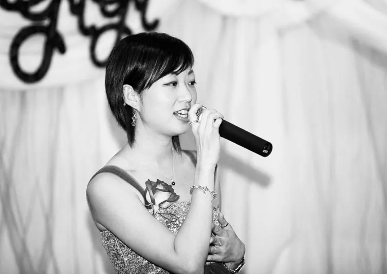Anita Tong singing at an evening wedding reception, microphone in hand